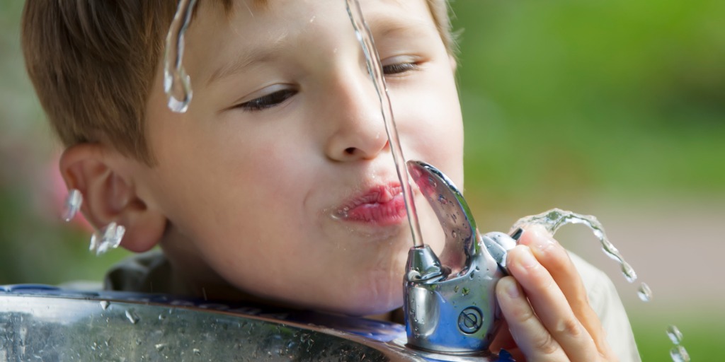 child drinking from water bubbler