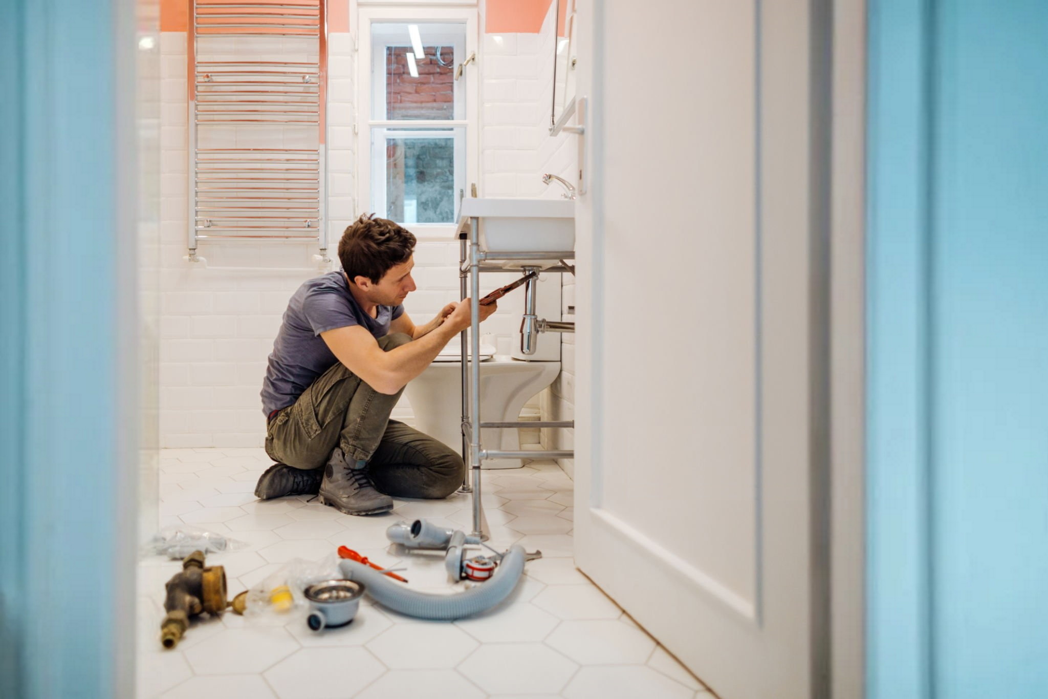 young man fixing a leak under the bathroom sink